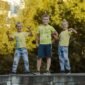 2 boys standing on gray concrete fence during daytime